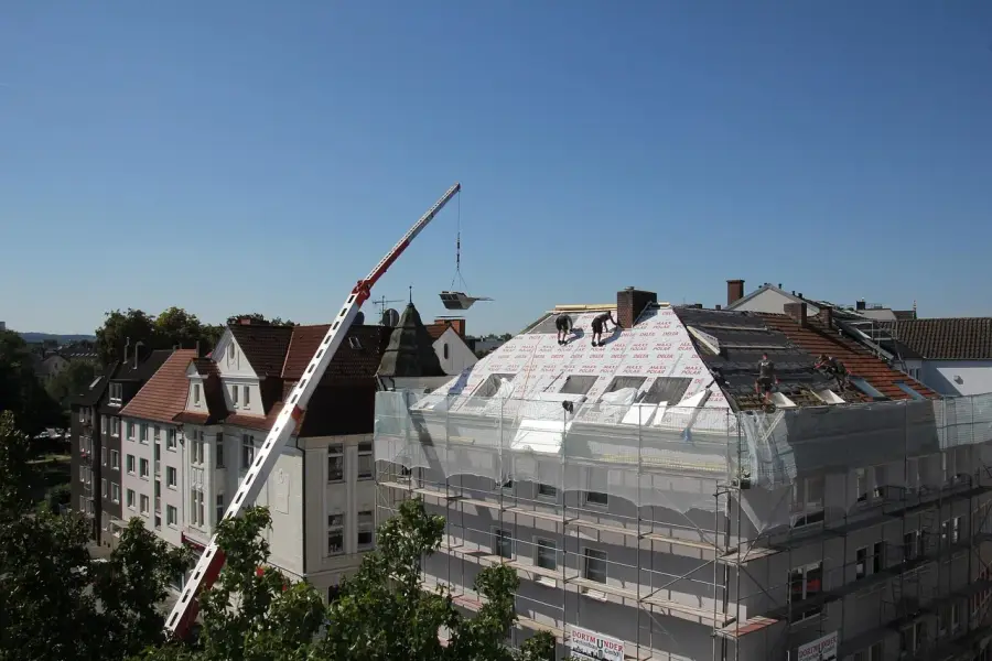 Dakdekkers brengen isolatiewol aan tijdens een dakrenovatie