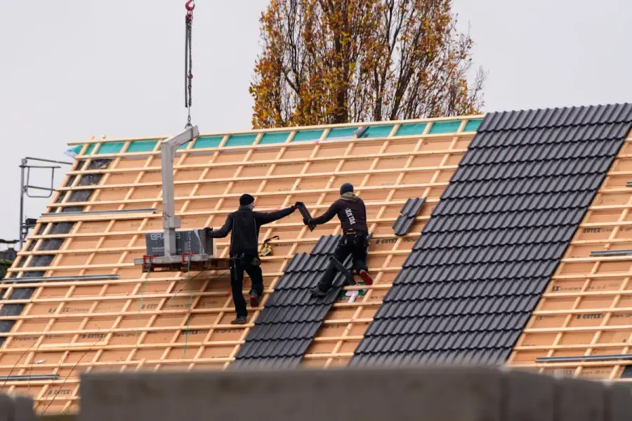 Dakdekkers plaatsen nieuwe dakpannen op een gebouw
