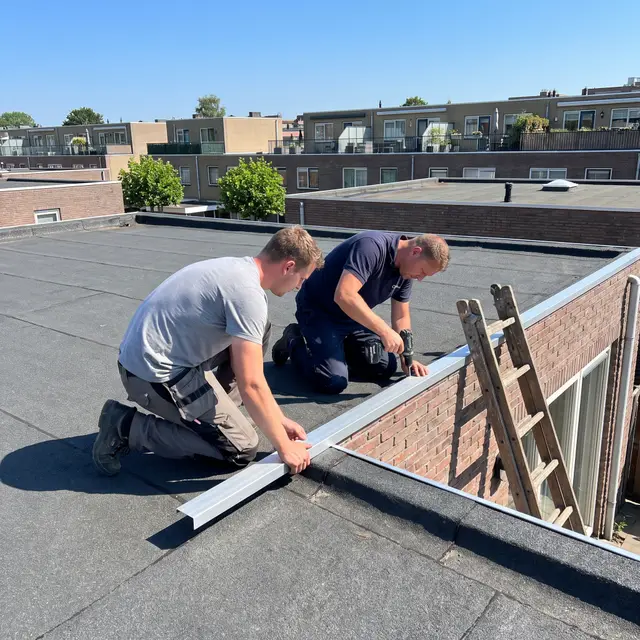 Twee dakdekkers werken samen aan de afwerking van de dakrand